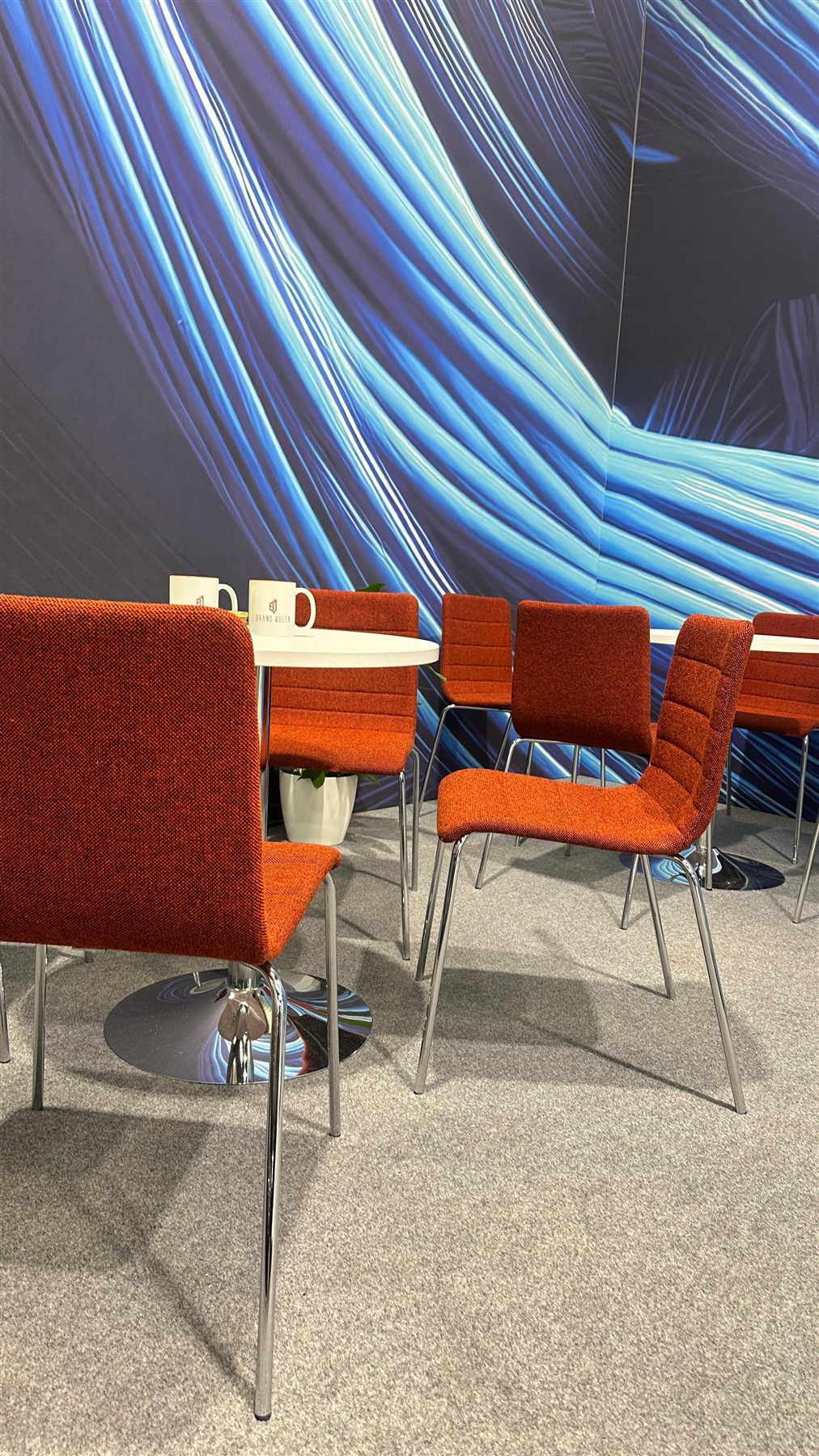 Loungebereich mit roten Stühlen und blauer Wandgrafik am CAD CABEL Stand