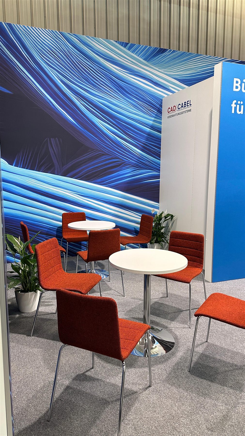 Sitzbereich am CAD CABEL Messestand mit fließendem blauen Motiv