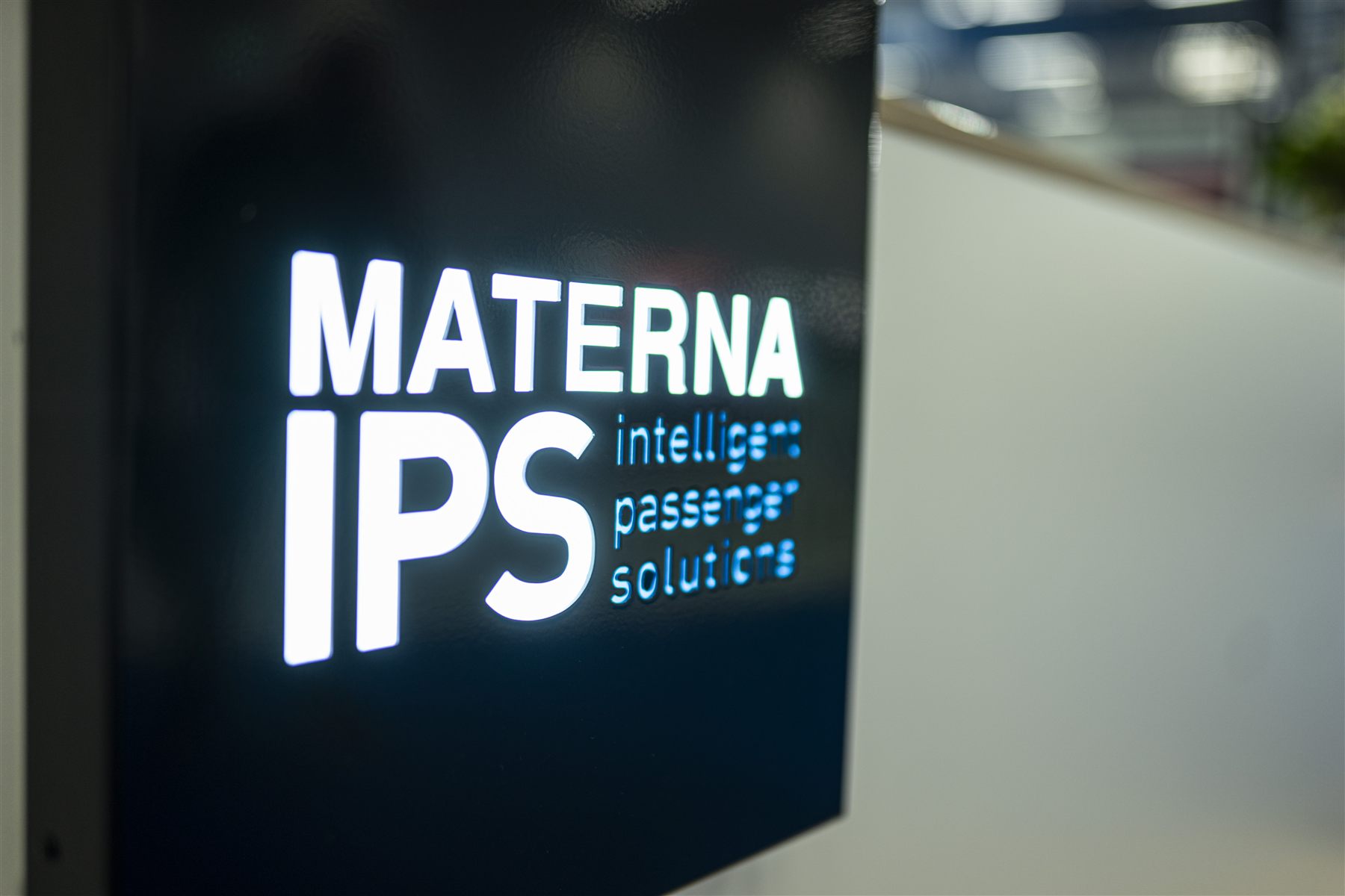 Beleuchtetes Logo Materna IPS intelligent passenger solutions am Messestand