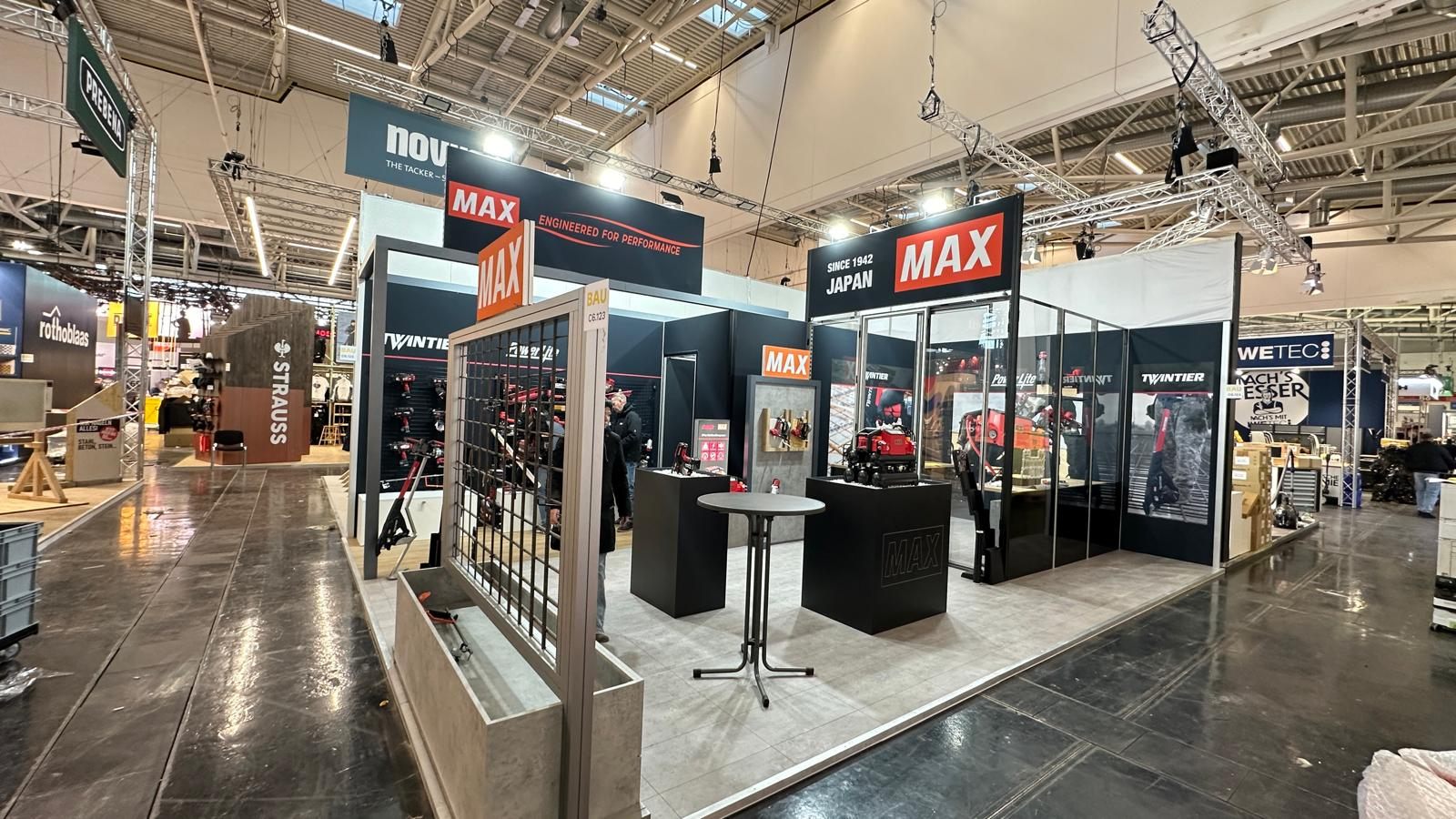Messestand für MAX auf der BAU München 2025, dunkler Rahmen mit rotem Markenakzent