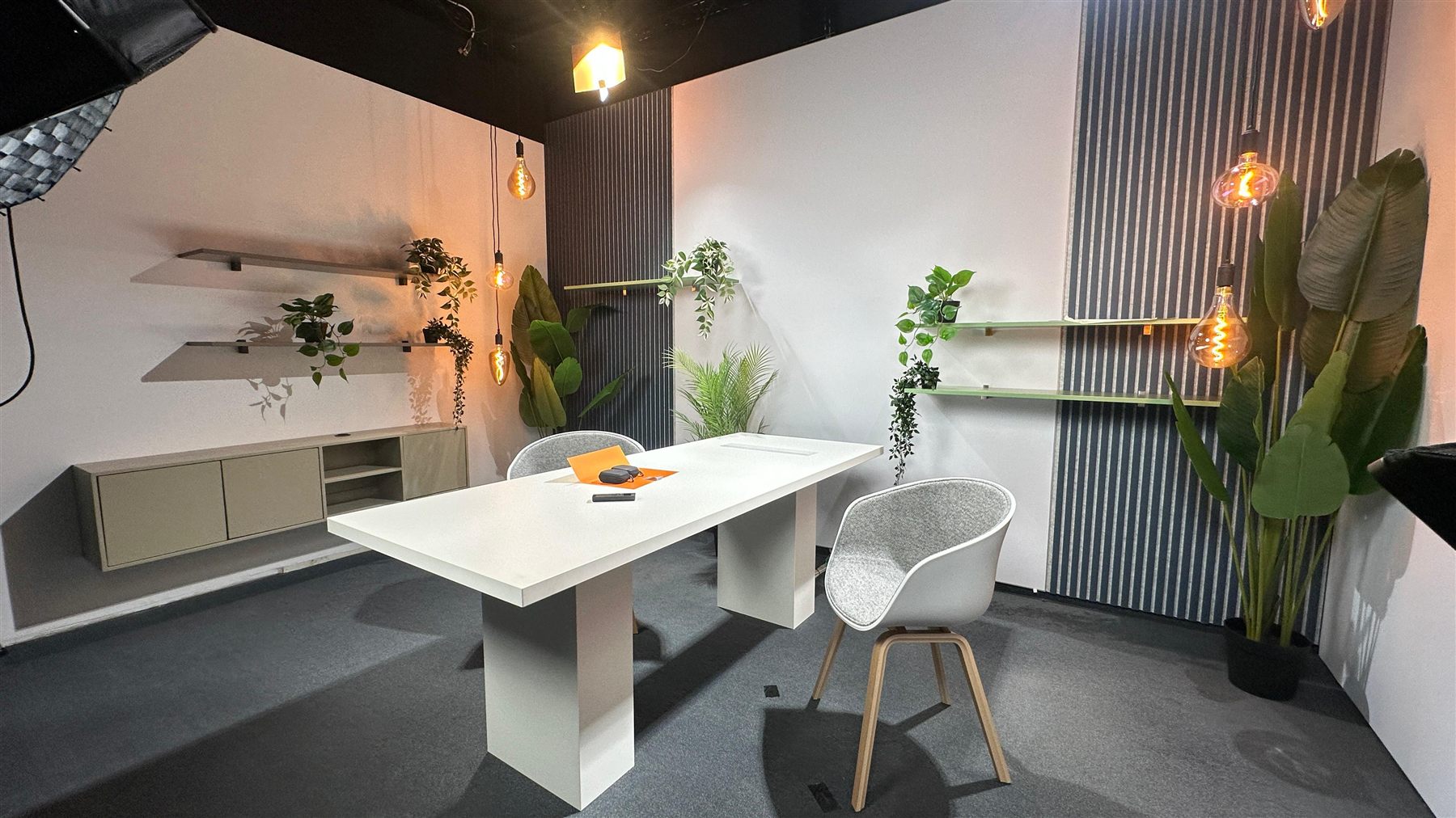 Studiobereich von MDT mit Tisch, Regal und Pflanzen in warmem Licht